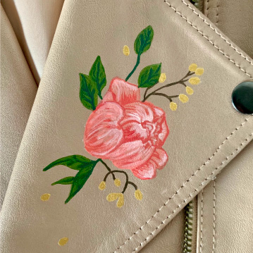 Painted flower on lapel of tan leather jacket.