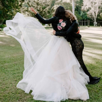 Two girls wearing painted leather jackets at a wedding.